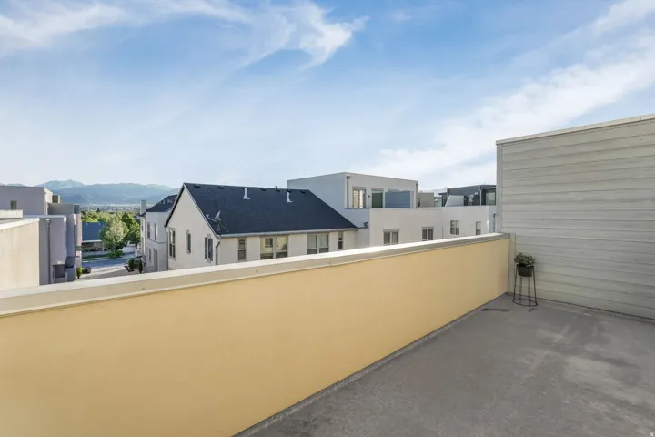 Rooftop patio featuring expansive concrete surfacing, a light yellow parapet wall, and an adjacent siding-clad wall