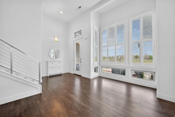 Expansive entry with rich wood-finish flooring, high ceilings, and a contemporary staircase featuring cable railing
