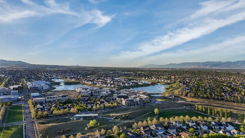 Expansive aerial panorama showcasing a developed community with multiple residential neighborhoods and a central lake feature