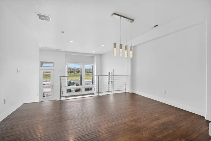 Open-concept interior featuring rich wood-finish flooring, a modern linear pendant light fixture, and recessed lighting
