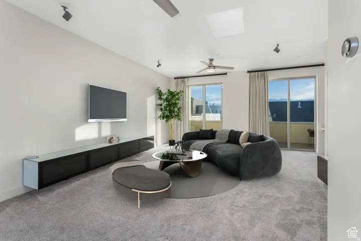 Spacious living area featuring light gray carpeting, a built-in media console, multiple sliding glass doors, a ceiling fan, and recessed lighting