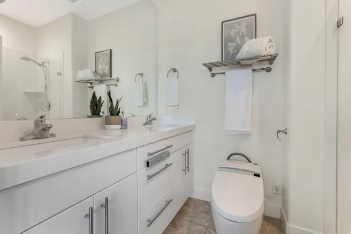 Bathroom featuring a dual vanity with white cabinetry, integrated sinks, and polished chrome fixtures