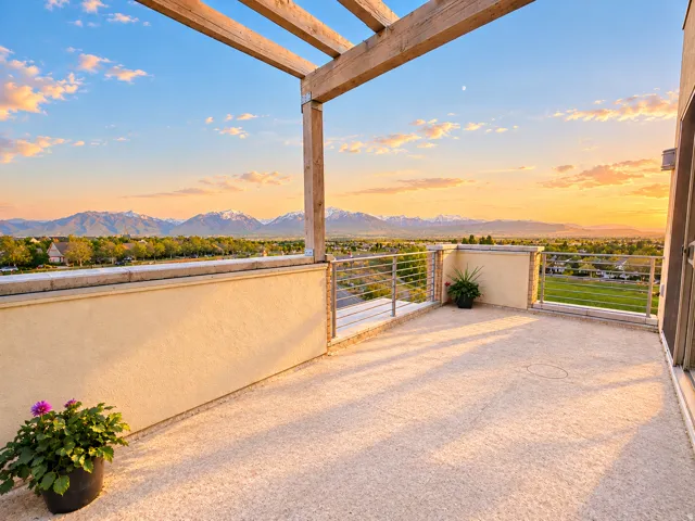Expansive rooftop terrace with a wood pergola, cable railing, and surrounding mountain scenery