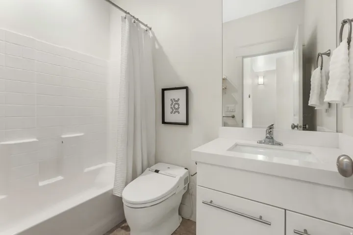 Modern bathroom featuring a white vanity with an integrated sink, polished chrome faucet, and a large wall-mounted mirror