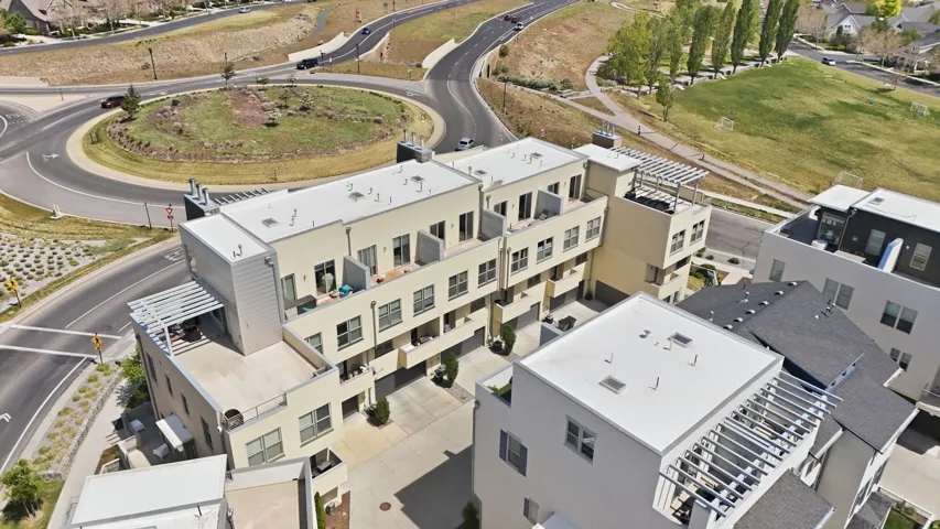 Modern multi-story residential complex featuring multiple private balconies, rooftop patios with pergolas, and an integrated parking area