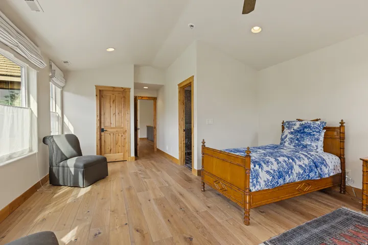 Spacious room featuring wood-finish flooring, white walls, and natural wood doors with dark hardware