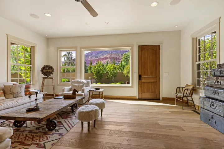 Spacious living area featuring wood-finish flooring, recessed lighting, and multiple large windows with natural wood trim