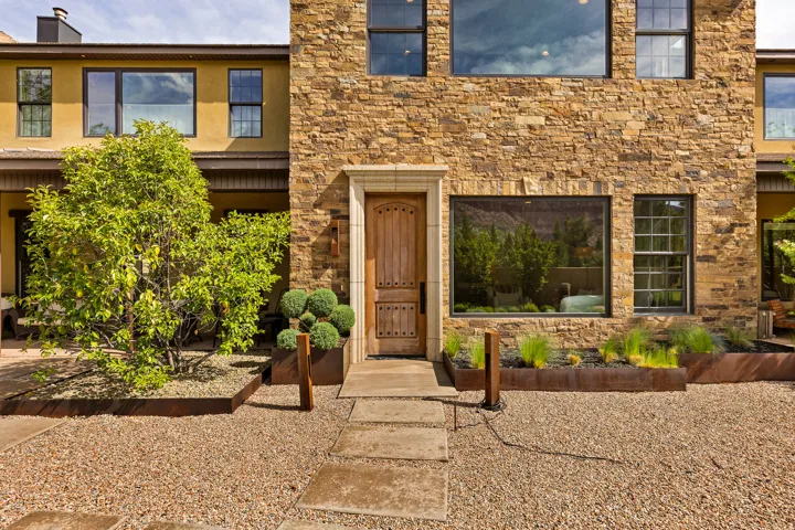 Stone veneer facade with a wood entry door featuring decorative hardware
