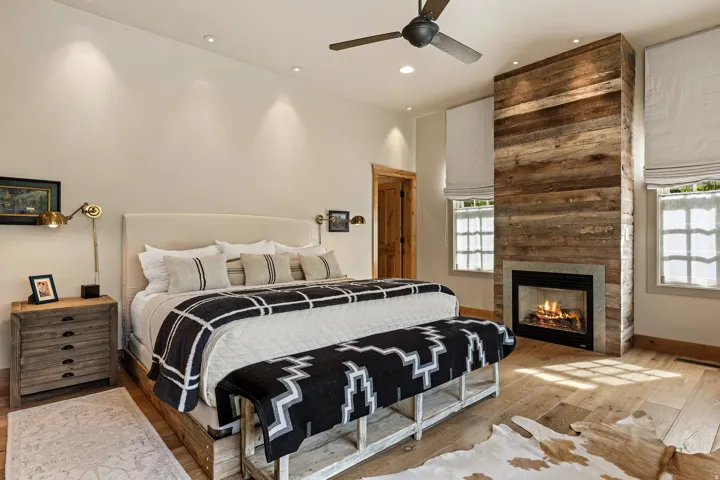 Bedroom featuring a floor-to-ceiling wood-paneled fireplace with a stone surround, light wood-finish flooring, and recessed ceiling lights