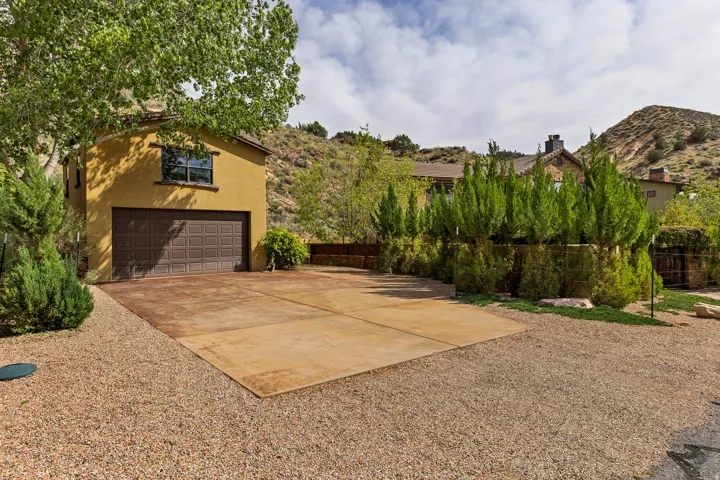 Stucco exterior with an attached garage, featuring a stamped concrete driveway and gravel landscaping