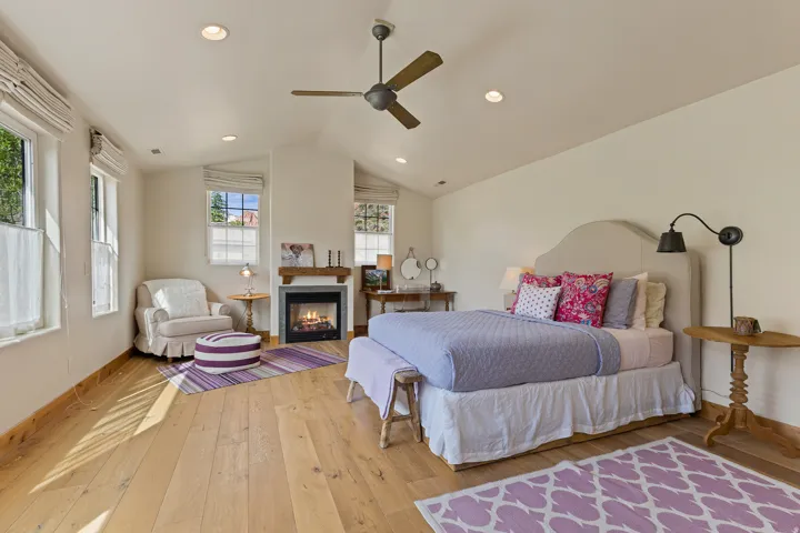 Spacious room featuring vaulted ceilings, wood-finish flooring, recessed lighting, and an integrated fireplace with a wood mantle