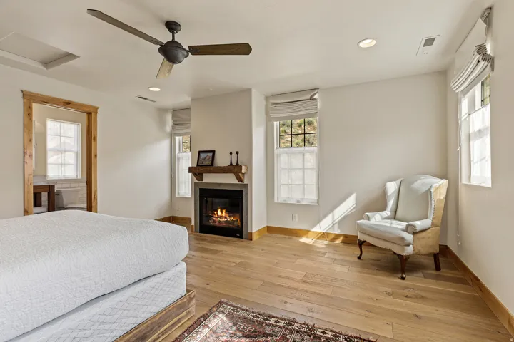 Bedroom featuring light wood-finish flooring, a ceiling fan, recessed lighting, and a fireplace with a wood mantle