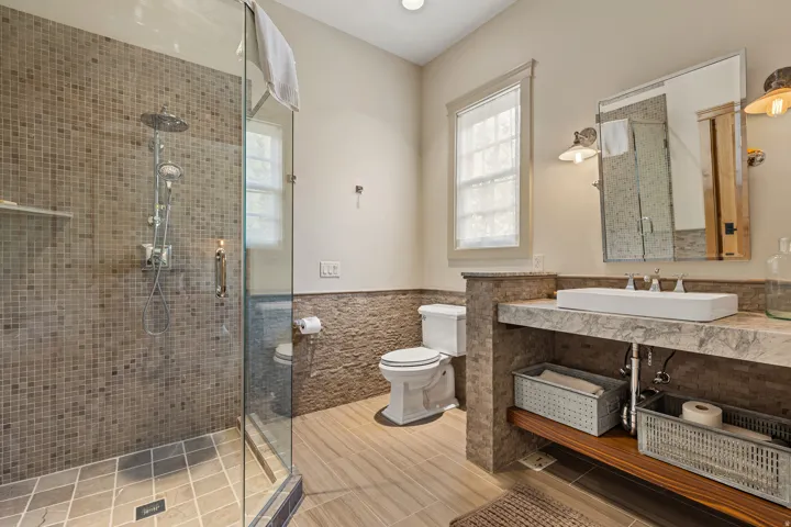Glass-enclosed shower featuring mosaic tile surround and rain showerhead