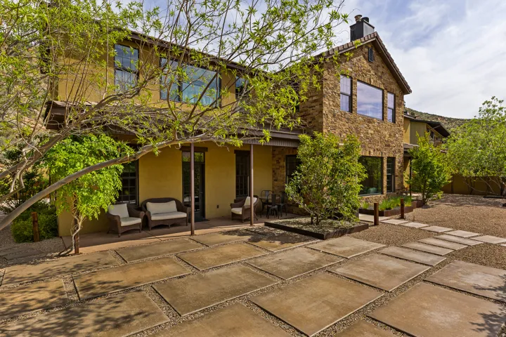 Stone and stucco exterior with multiple large windows, a covered patio, and a stone chimney