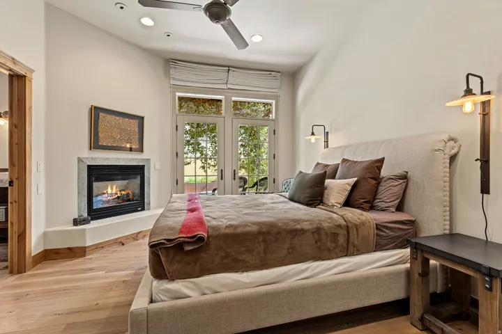 Room featuring wood-finish flooring, a corner-set fireplace with a stone surround, and double French doors with transom windows