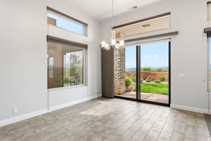Spacious room featuring large format tile flooring, a contemporary chandelier, and a stone-clad architectural detail