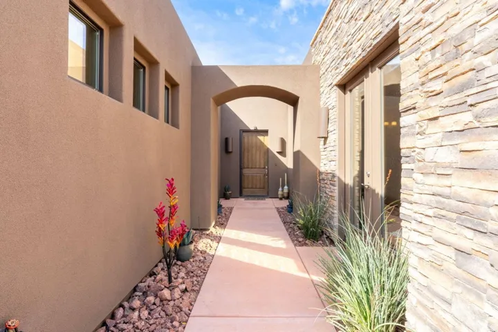 Entryway featuring a stucco exterior, a stone accent wall, an arched passage, a wooden entry door, and a concrete walkway