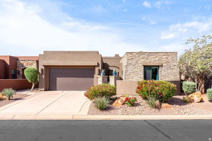 Front exterior featuring a stucco facade with stone accents, an attached garage, and a concrete driveway