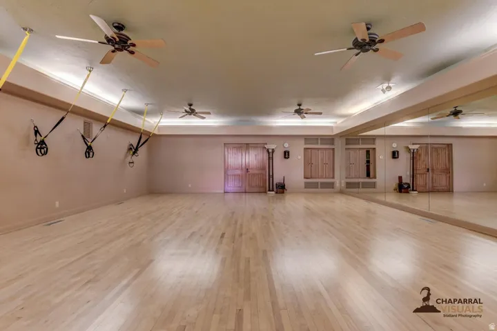 Spacious room with wood-finish flooring, full-length wall mirrors, and recessed lighting