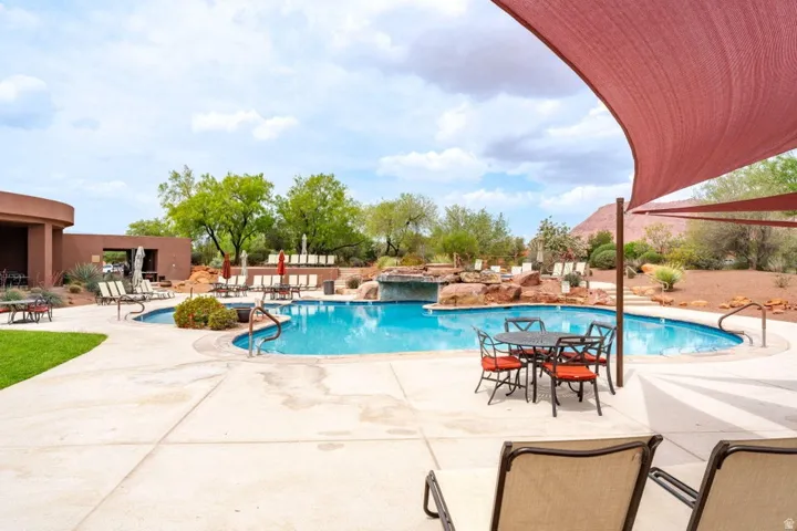 Resort-style pool area featuring a freeform swimming pool, integrated spa, rock waterfall, and a surrounding concrete deck