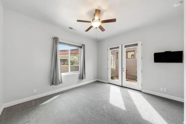 Neutral-toned carpeting extends throughout this interior space, featuring a ceiling fan with integrated lighting
