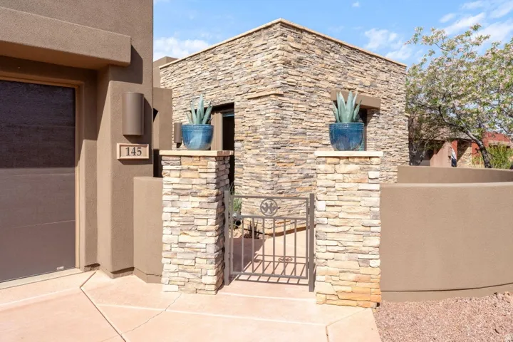 Stucco exterior with stone accents and a wrought iron gate