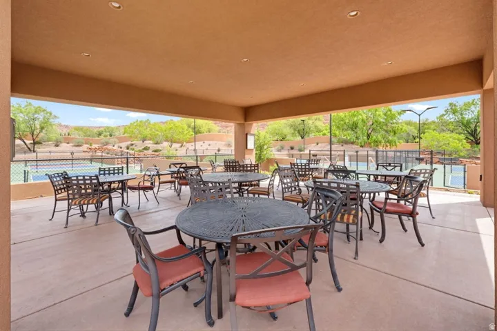 Spacious covered patio area with recessed lighting, concrete flooring, and an open perimeter overlooking outdoor courts and distant red rock formations