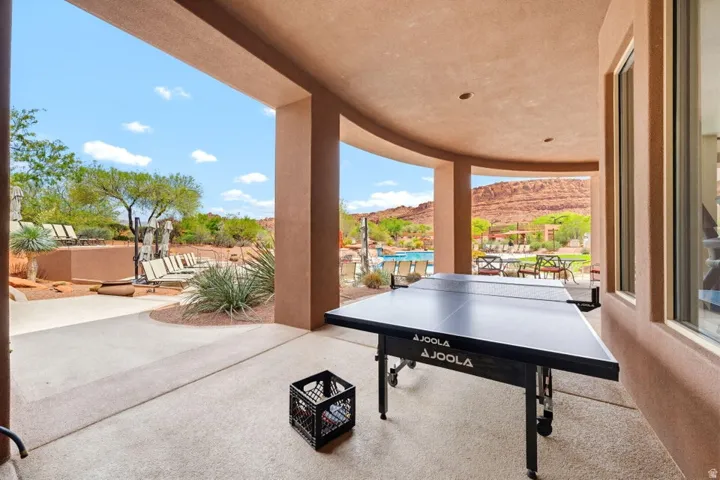 Expansive covered patio with recessed lighting, offering an outdoor dining area, a pool area, and desert landscaping