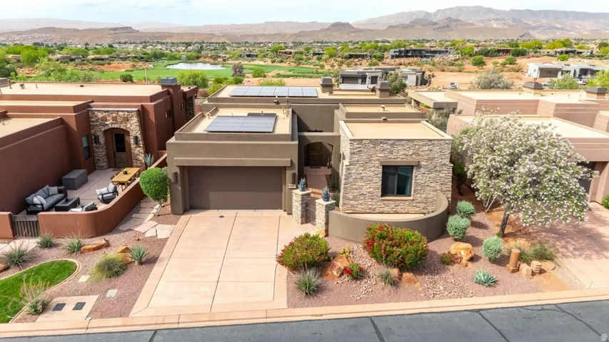 Contemporary desert architecture featuring a stucco exterior with stone accents, a two-car garage, and a concrete driveway