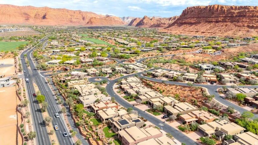 Expansive residential area featuring numerous single-story homes with flat roofs, integrated into a desert landscape with natural rock formations