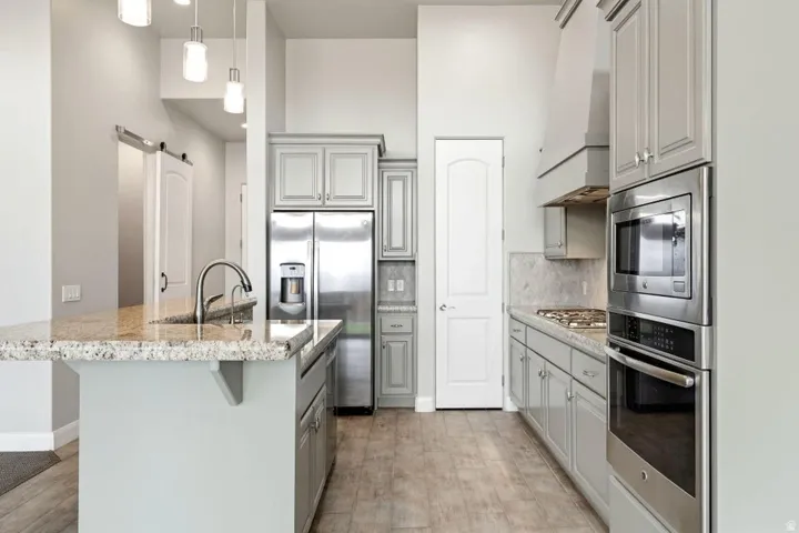 Kitchen featuring a granite-topped island with an undermount sink and gooseneck faucet