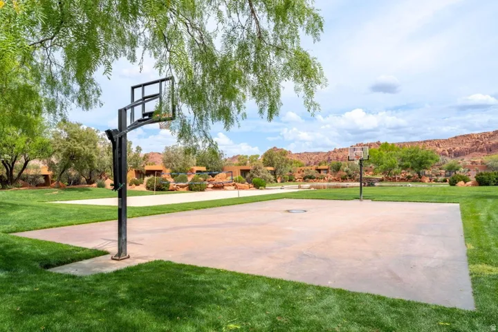 Outdoor concrete basketball court set within a manicured lawn