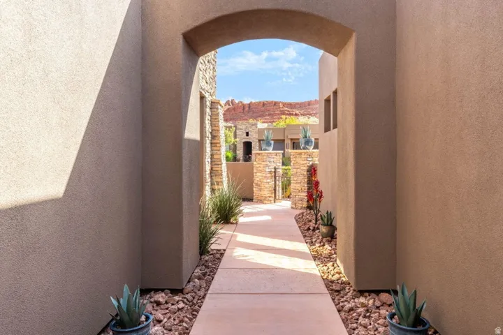Arched entryway framing a stone-clad exterior with a concrete walkway