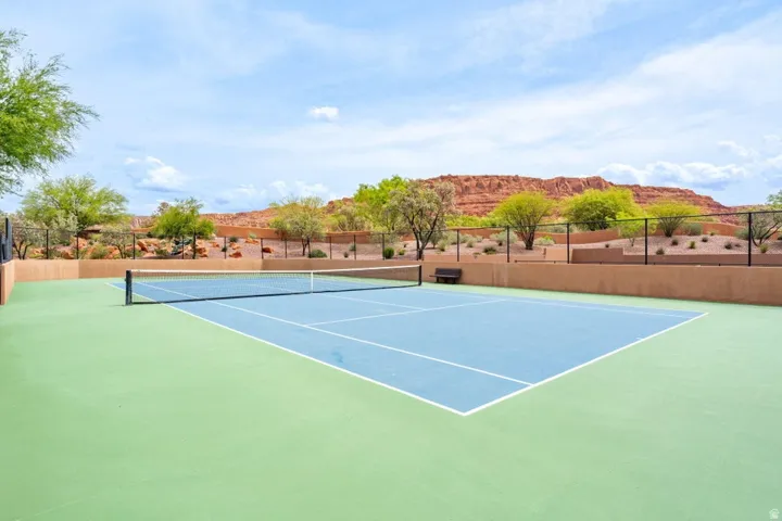 Regulation-size tennis court featuring a blue playing surface with white lines and green perimeter