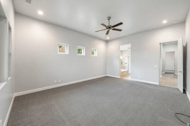 Spacious interior room featuring light-toned walls and grey carpet flooring