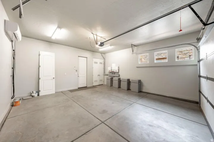 Spacious garage featuring a concrete floor, multiple access doors, and three horizontal transom windows