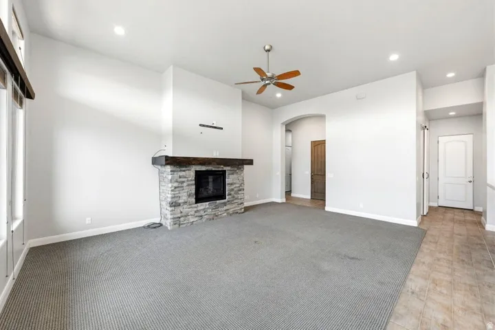Living area featuring a stone-clad fireplace with a wood mantel, recessed lighting, and a ceiling fan