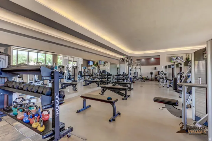 Dedicated fitness center with extensive exercise equipment, recessed ceiling lighting, large exterior windows, a mirrored wall, and wall-mounted televisions