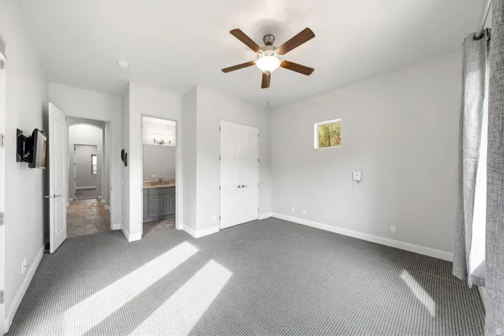 Spacious room featuring neutral carpeting, a ceiling fan with integrated lighting, and a white interior door
