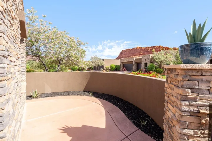 Exterior entry featuring stacked stone accents, smooth stucco finishes, and a curved concrete pathway