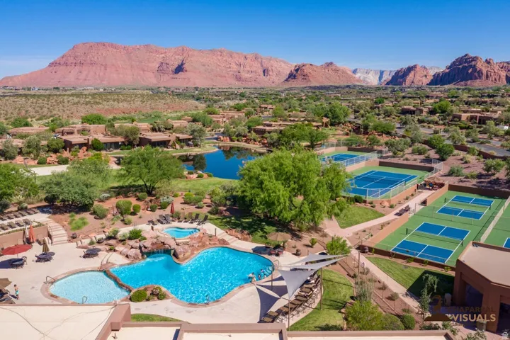 Expansive property featuring a multi-level swimming pool with rock detailing, multiple tennis courts, pickleball courts, and a tranquil pond
