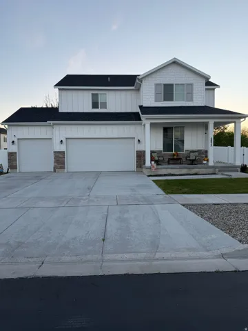 Modern farmhouse exterior featuring white board and batten siding, dark shingle roofing, and stone accents