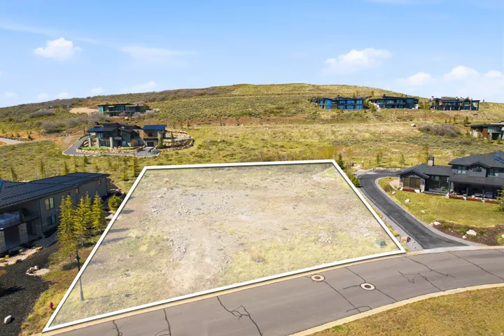 Expansive building lot with visible boundary lines, featuring a clear, level building area and paved street access