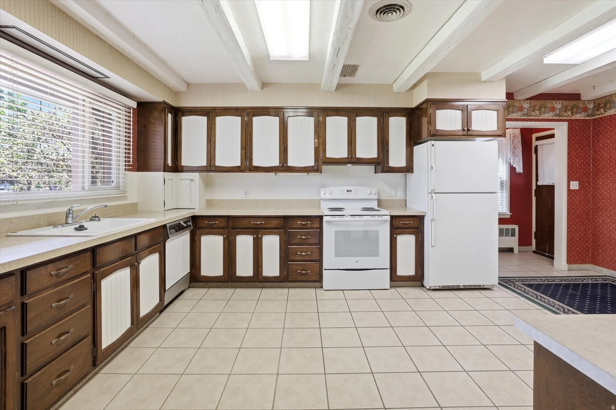 Kitchen featuring extensive wood cabinetry with white panel inserts, light-toned countertop surfaces, and a white tile floor