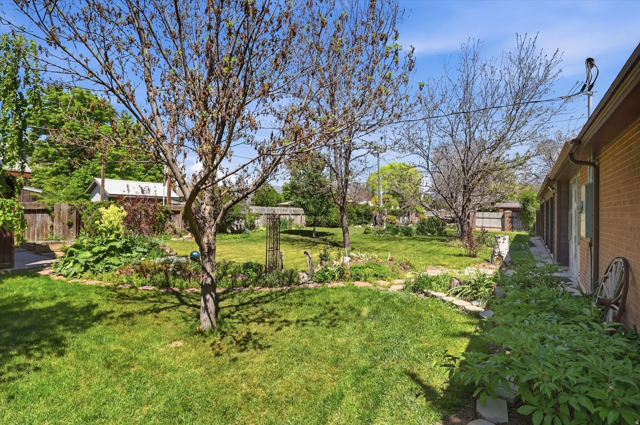 Expansive backyard featuring a manicured lawn, established trees, and mature landscaping