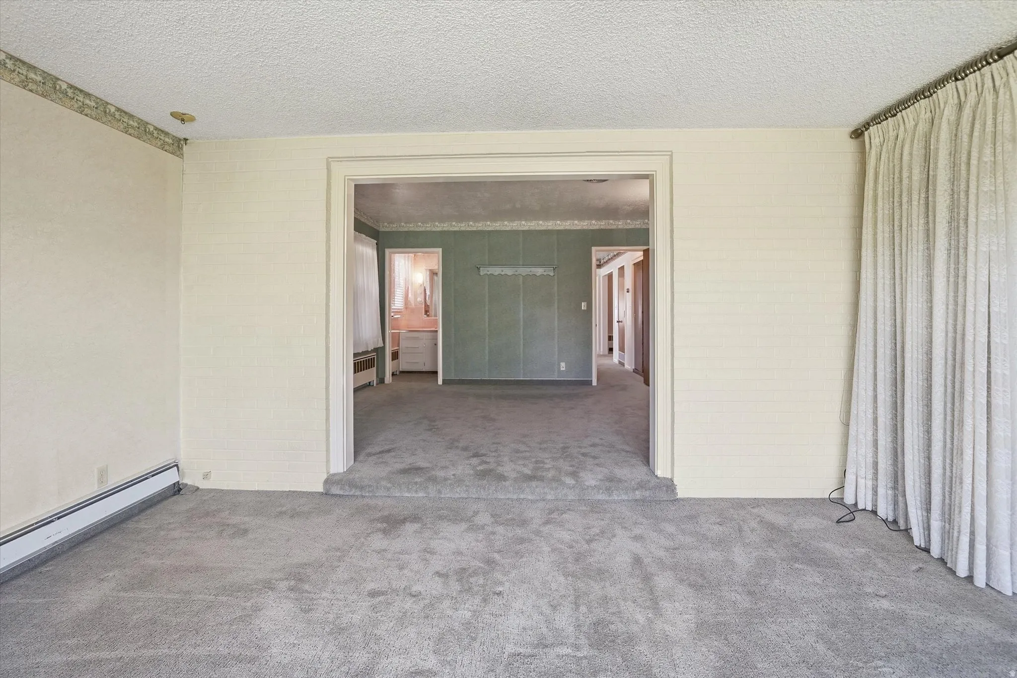 Carpeted interior space with a broad doorway opening into an additional room
