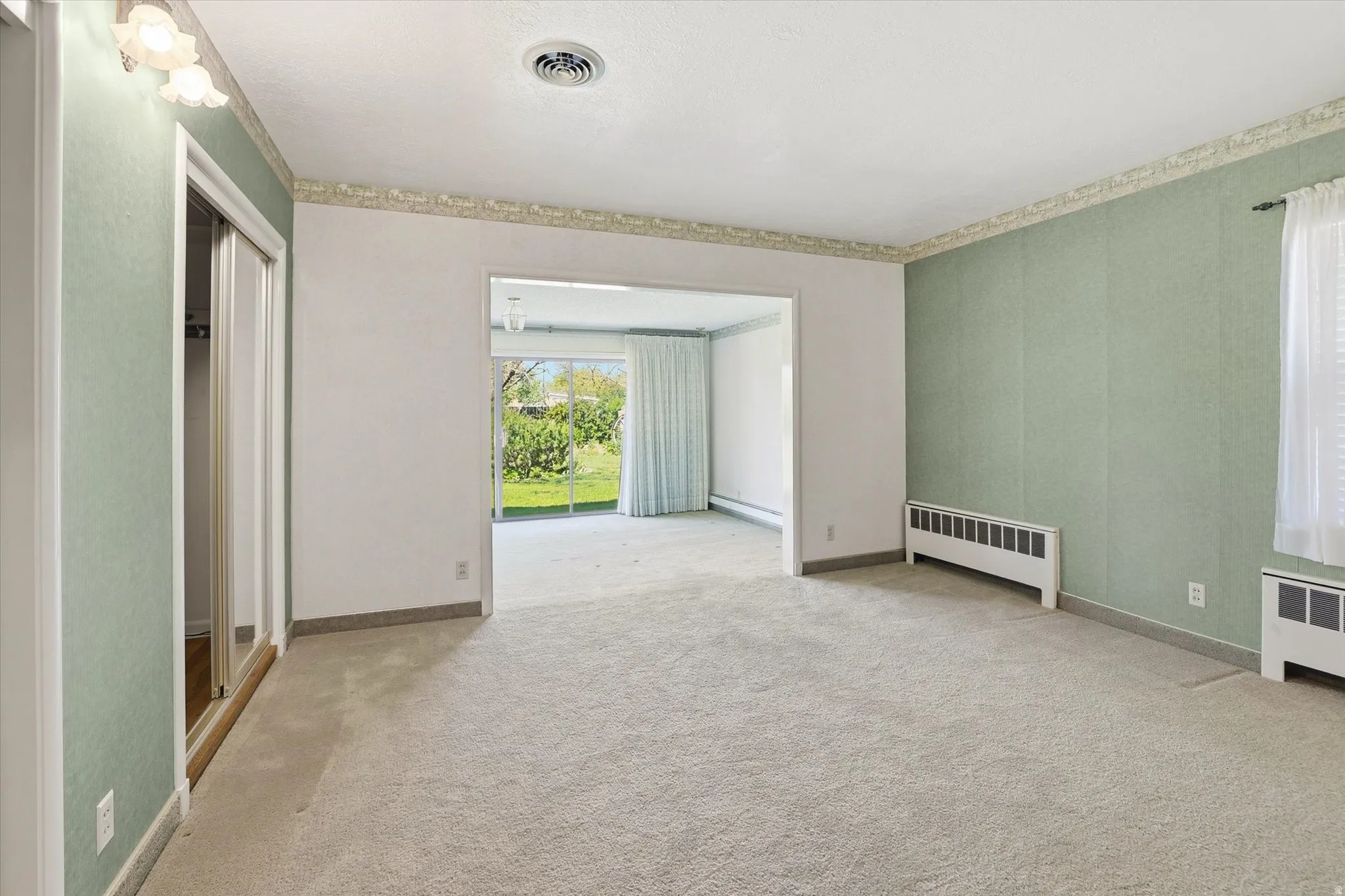 Carpeted room with light green walls, a white ceiling, and a wall-mounted light fixture