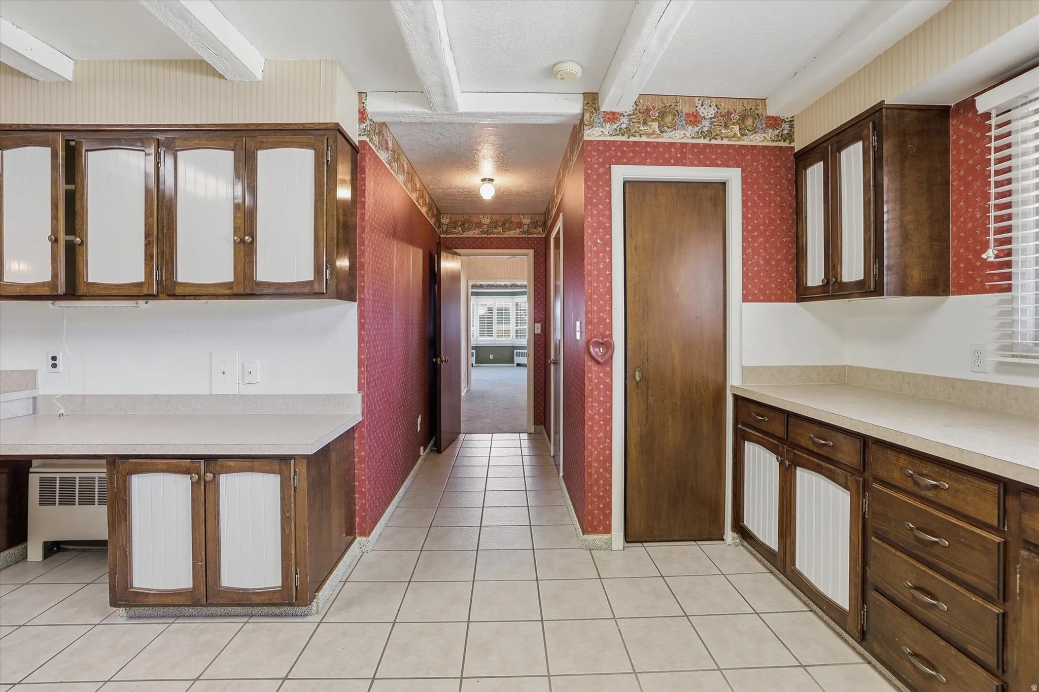 Kitchen with extensive wood cabinetry, light-toned countertops, and square tile flooring