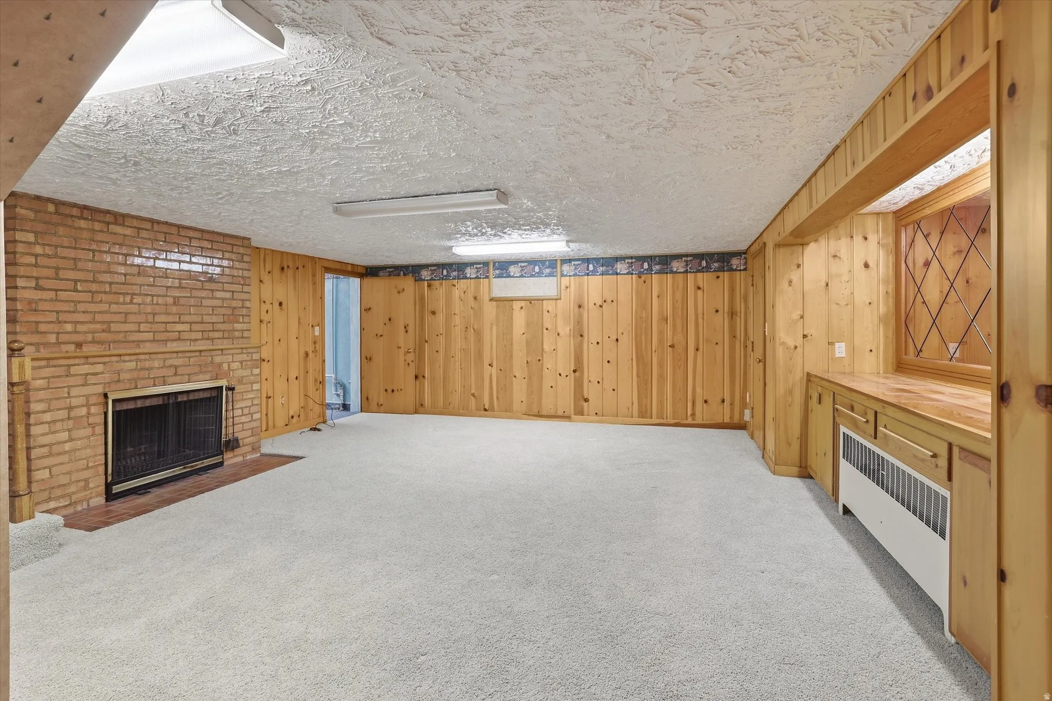 Expansive room featuring light-toned carpeting and wood-paneled walls