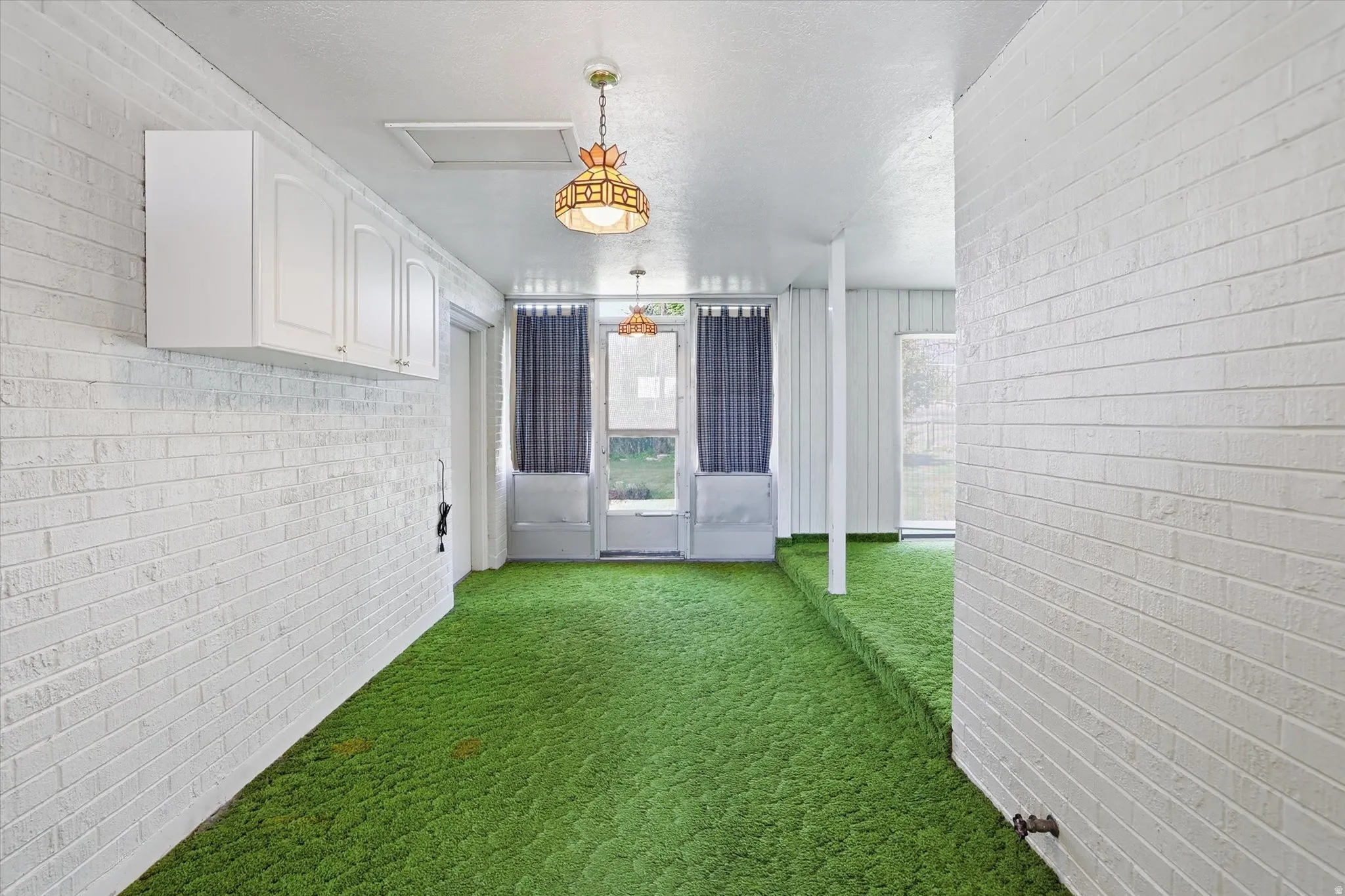 Interior space featuring white brick-patterned walls and vibrant green carpeting